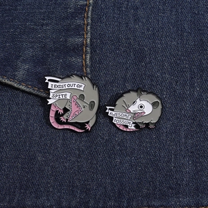Detail of funny opossum enamel pins on denim, showing colorful cartoon design and textures