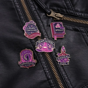 Close-up of wizard themed enamel pins including crystal ball and spells book on leather