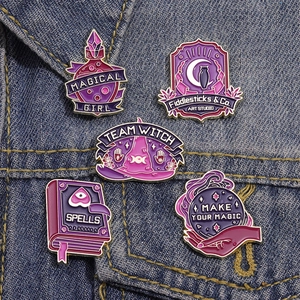 Detail of five magical enamel pins including spell book and potion on blue denim jacket