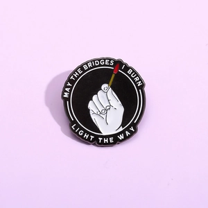 Geometric round enamel pin featuring a hand and matchstick with motivational quote