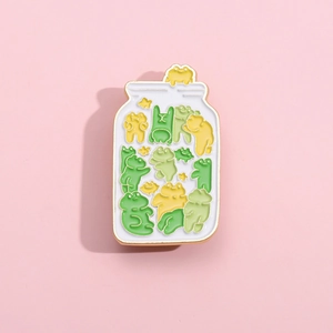 Cute enamel pin featuring several colorful frogs in a white jar on a pink background