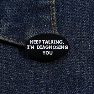 Détail du pin's en émail noir avec texte blanc KEEP TALKING sur tissu en jean bleu