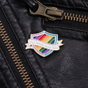 Macro detail of rainbow shield enamel pin with text I'll Walk With You on black leather
