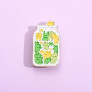 Creative enamel pin featuring cute frogs in a jar with golden metal edges on purple background