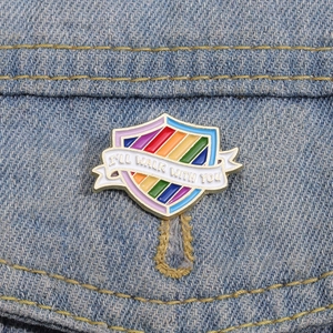 Detail of rainbow shield enamel pin with I'LL WALK WITH YOU text on denim fabric