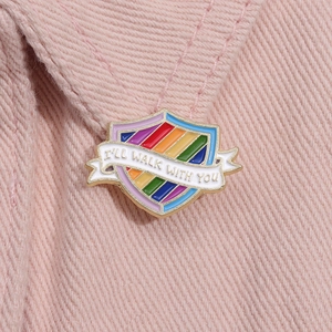 Detail of I'LL WALK WITH YOU rainbow shield enamel pin on pink corduroy fabric