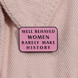 Macro shot of pink enamel pin with black 'Well behaved women rarely make history' quote