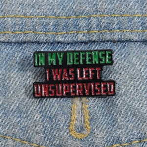 Detail of enamel pin with 'In My Defense I Was Left Unsupervised' text on denim jacket