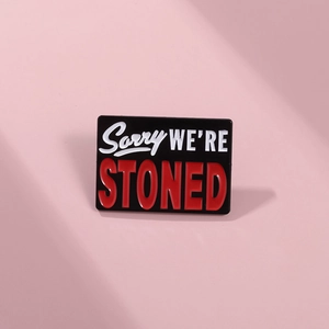 Detail of Sorry We're Stoned enamel pin brooch on a soft pink background with shadows