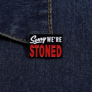 Detail of Sorry We're Stoned enamel pin on blue denim fabric with clear metal edges