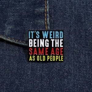 Close-up of square enamel pin with funny slogan attached to a denim jacket