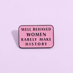 Pink enamel pin featuring Well Behaved Women Rarely Make History quote on purple background