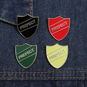 Close-up of shield-shaped enamel pins in four colors on blue denim fabric