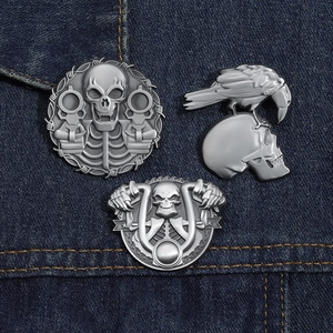 Three punk skull pins on denim jacket showing detailed gothic and motorcycle designs