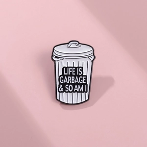 Detail of trash can enamel pin with Life Is Garbage slogan on pink background