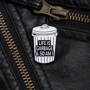 Close-up of Life is Garbage trash can enamel pin on a black leather jacket texture