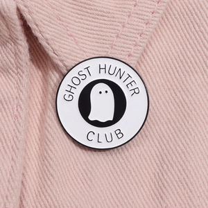 Dettaglio macro della spilla smaltata Ghost Hunter Club bianca su tessuto denim rosa
