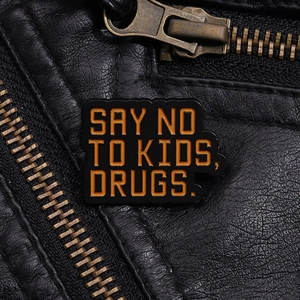 Detail of enamel pin with orange text on black leather jacket, creative quote design