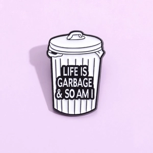 Creative trash can metal brooch with Life Is Garbage funny quote on purple background