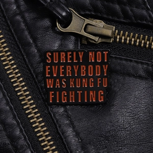 Close-up of enamel pin with quote on black leather jacket showing texture and detail