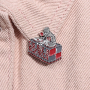 Detail of Monty Python Black Knight DJ enamel pin on pink denim with 'TIS BUT A SCRATCH' text