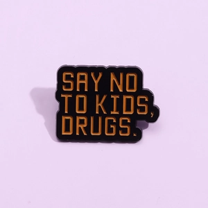 Funny enamel pin with Say No To Kids slogan and gold metal edge on purple background