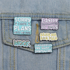Detail of 5-piece dog themed colorful enamel pins pinned on a denim jacket pocket