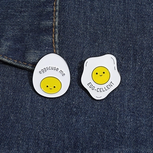 Detail of funny enamel pins featuring egg-shaped faces on denim background
