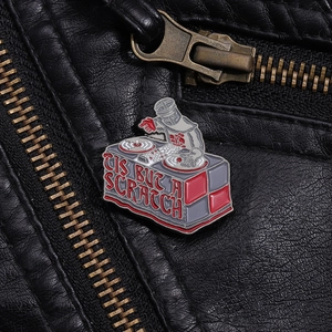 Detail of enamel Black Knight DJ pin with TIS BUT A SCRATCH text on leather jacket