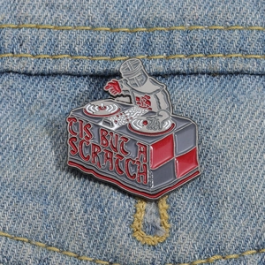 Detail of creative Black Knight DJ enamel pin with red text on blue denim fabric