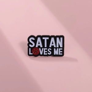 Macro detail of Satan Loves Me enamel pin with red pentagram on pink background