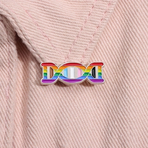 Macro detail of a rainbow gradient DNA helix enamel pin on pink denim fabric material