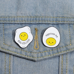 Detail of creative fried egg enamel pins with pun text on blue denim jacket pocket