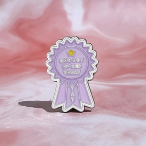 Detail view of purple award medal enamel pin with Got Out Of Bed Today text