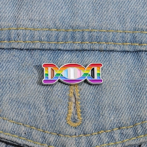 Detailed shot of rainbow DNA double helix enamel pin on a light blue denim jacket pocket