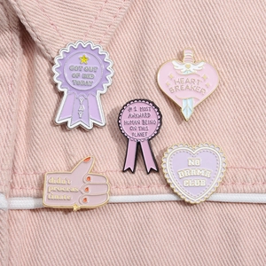 Detail of 5-piece enamel pin set with fun slogans on pink denim fabric background