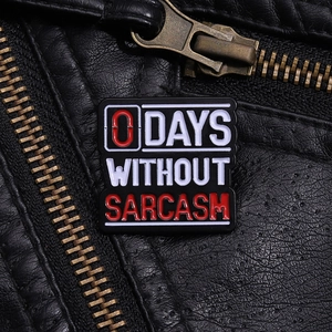 Detail shot of 0 Days Without Sarcasm enamel pin on a black leather jacket lapel