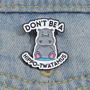 Macro shot of a cartoon hippo enamel pin on blue denim jacket with humorous text