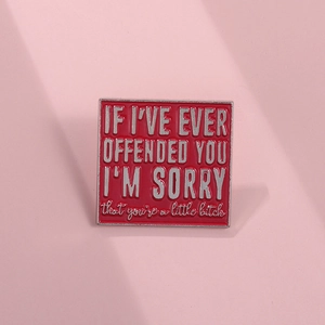 Macro shot of square red enamel brooch with bold silver typography on pink background