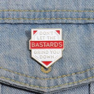 Shield enamel pin with motivational quote on a denim jacket pocket edge