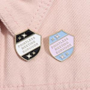 Macro shot of Pointless Meeting Survivor enamel pins on pink denim fabric surface
