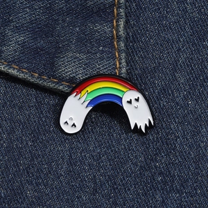 Close-up of rainbow ghost enamel pin with heart eyes on blue denim jacket texture