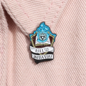 Détail de l'épinglette en émail en forme de bouclier avec dé d20 sur denim rose