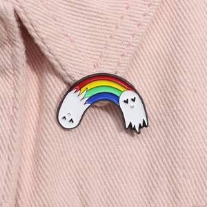 Close-up of a creative rainbow ghost enamel brooch with heart eyes on pink fabric background