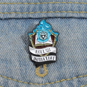 Détail macro du pin's émaillé Roll for Initiative avec dé d20 sur tissu en denim