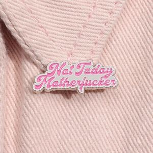 Makroaufnahme der rosa Emaille-Anstecknadel mit Text auf rosa Denim-Stoff