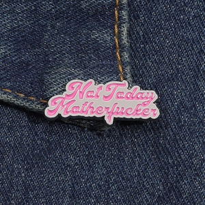 Detail von pinker Emaille-Anstecknadel mit Spruch auf blauem Denim-Hintergrund