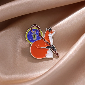 Macro shot of cartoon fox enamel pin holding a magic wand on champagne silk background
