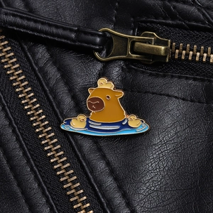 Close-up of cute enamel capybara and duck pin on black leather background