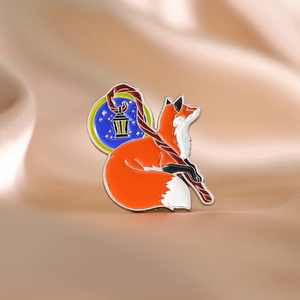 Macro shot of a cartoon fox enamel pin with a scepter on champagne silk fabric background